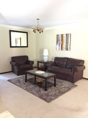 Relax in this inviting living room with a sofa, coffee table, and side table, accompanied by a large mirror and abstract art.