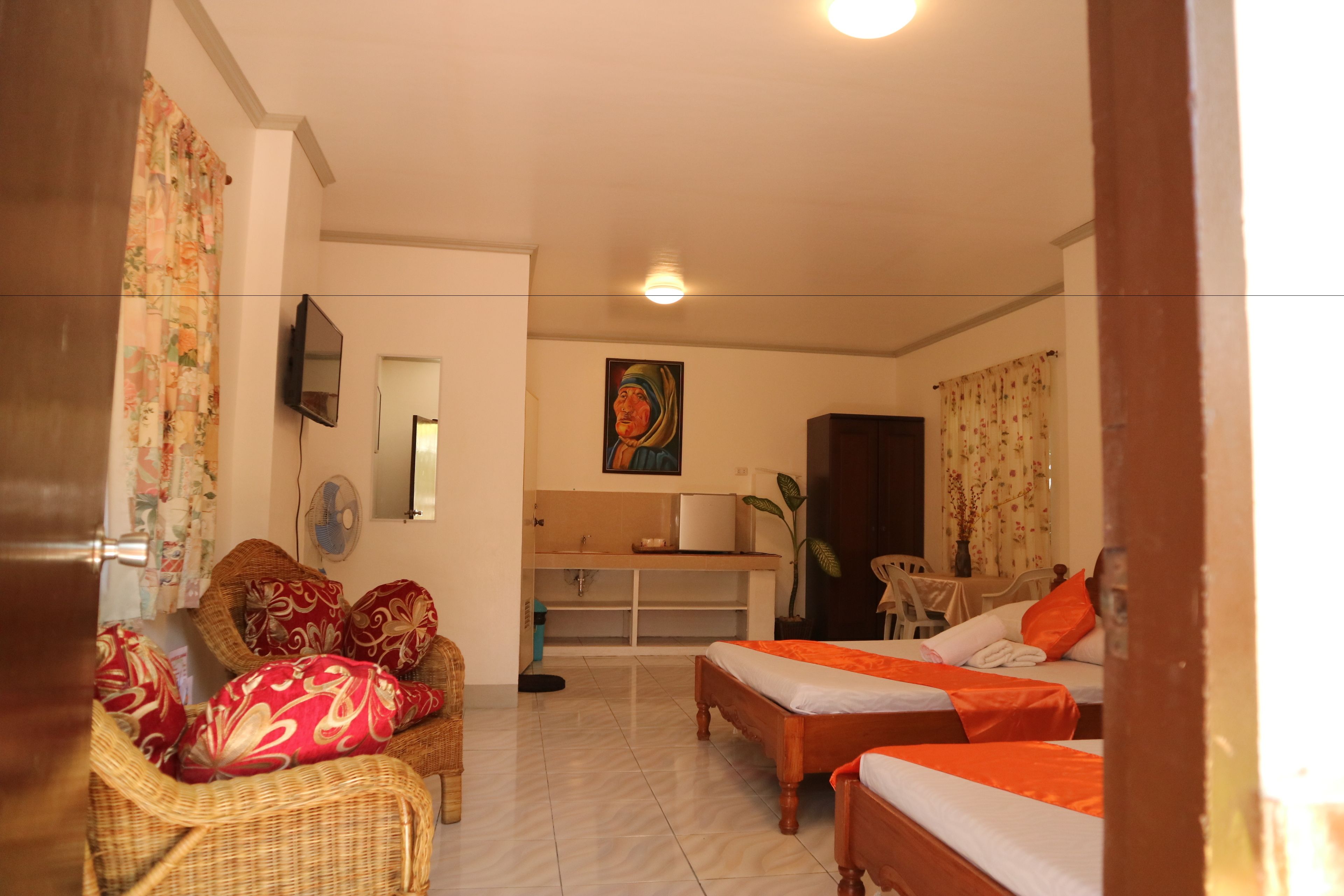 A hotel room with two single beds, a sofa, a TV, a desk, and a bathroom.
