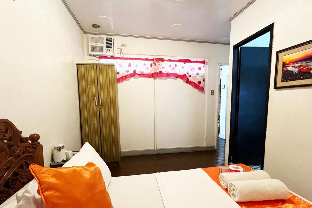 Une chambre d’hôtel comprenant un lit, un appareil de climatisation, une armoire et une porte donnant sur une autre pièce.