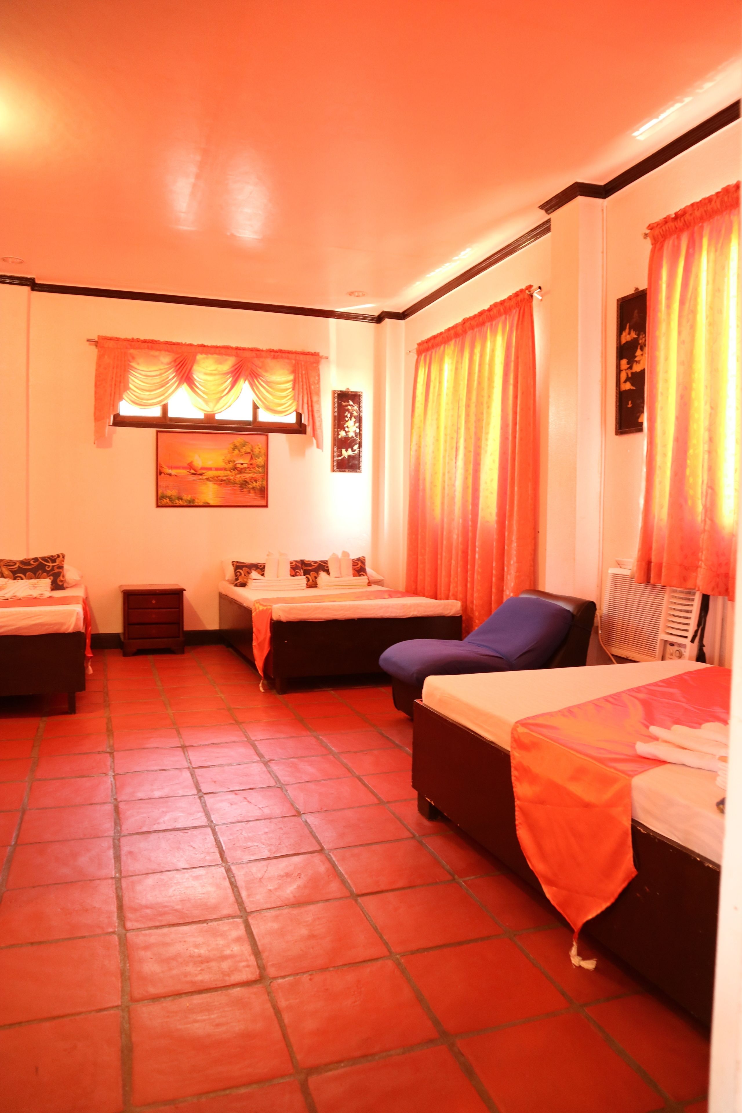 Una habitación de hotel con dos camas, una mesita, una silla y un cuadro en la pared.