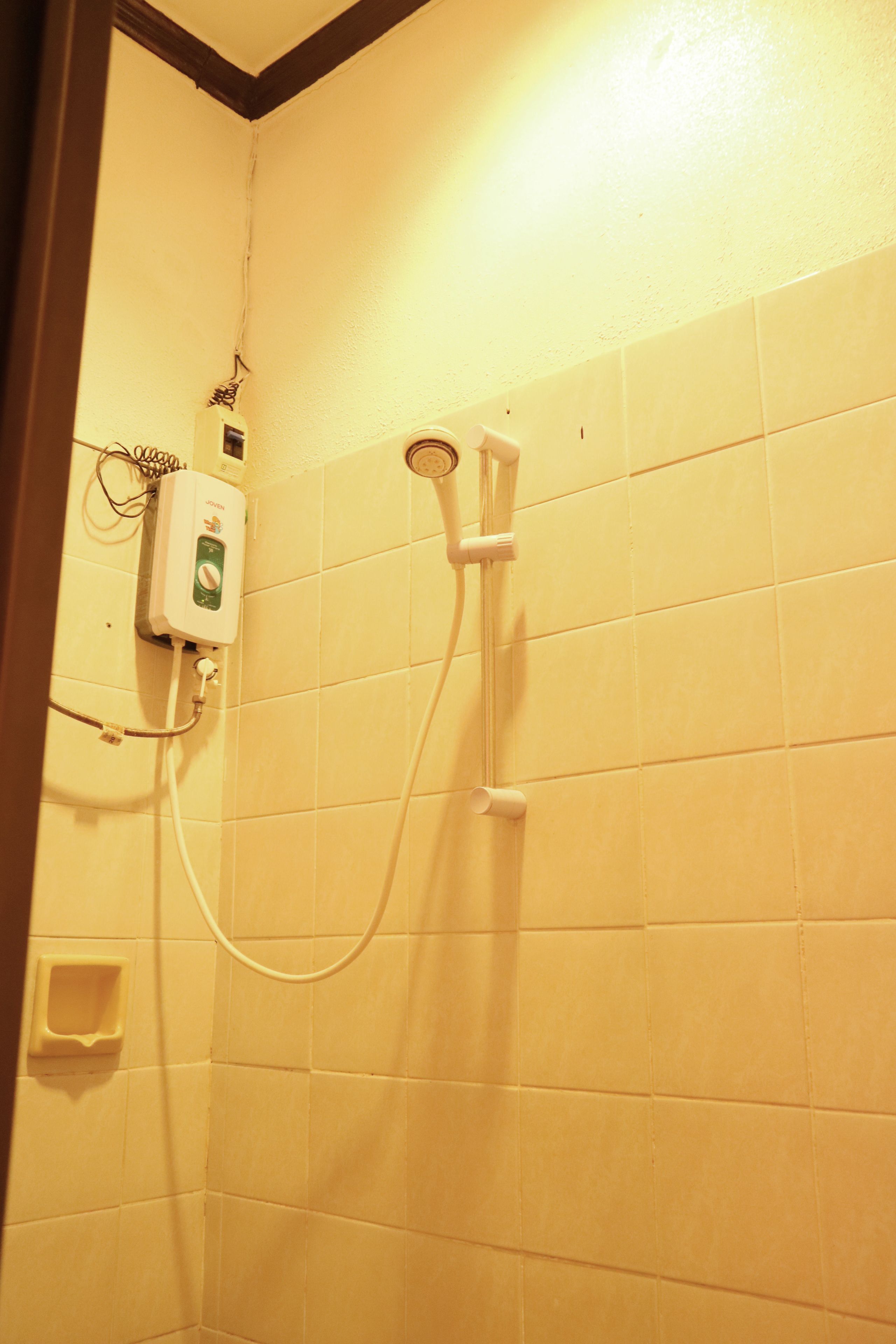 A bathroom with white tiles, a showerhead, and a control panel.