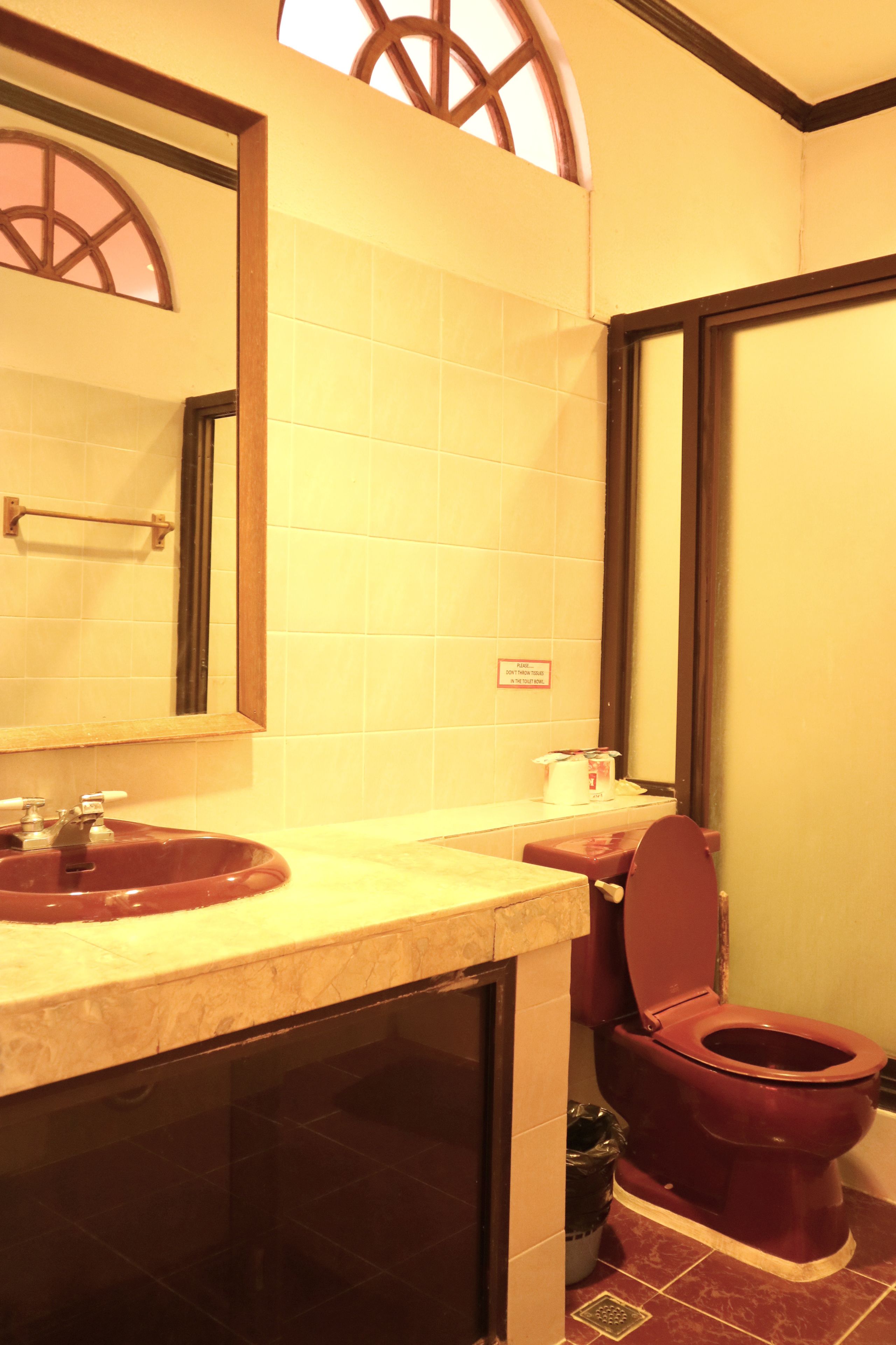 Een badkamer met een wastafel, spiegel, toilet en een raam met houten kader.