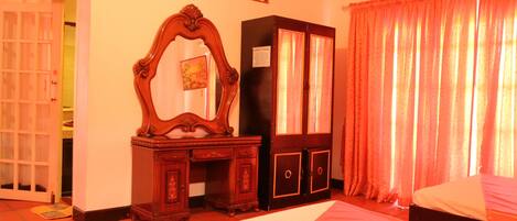 A hotel room with a bed, a wooden dresser, a mirror, and a wardrobe.