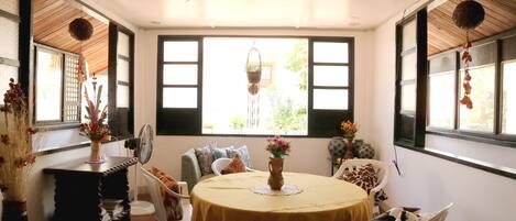 A dining area with a round table, chairs, and a vase with flowers.