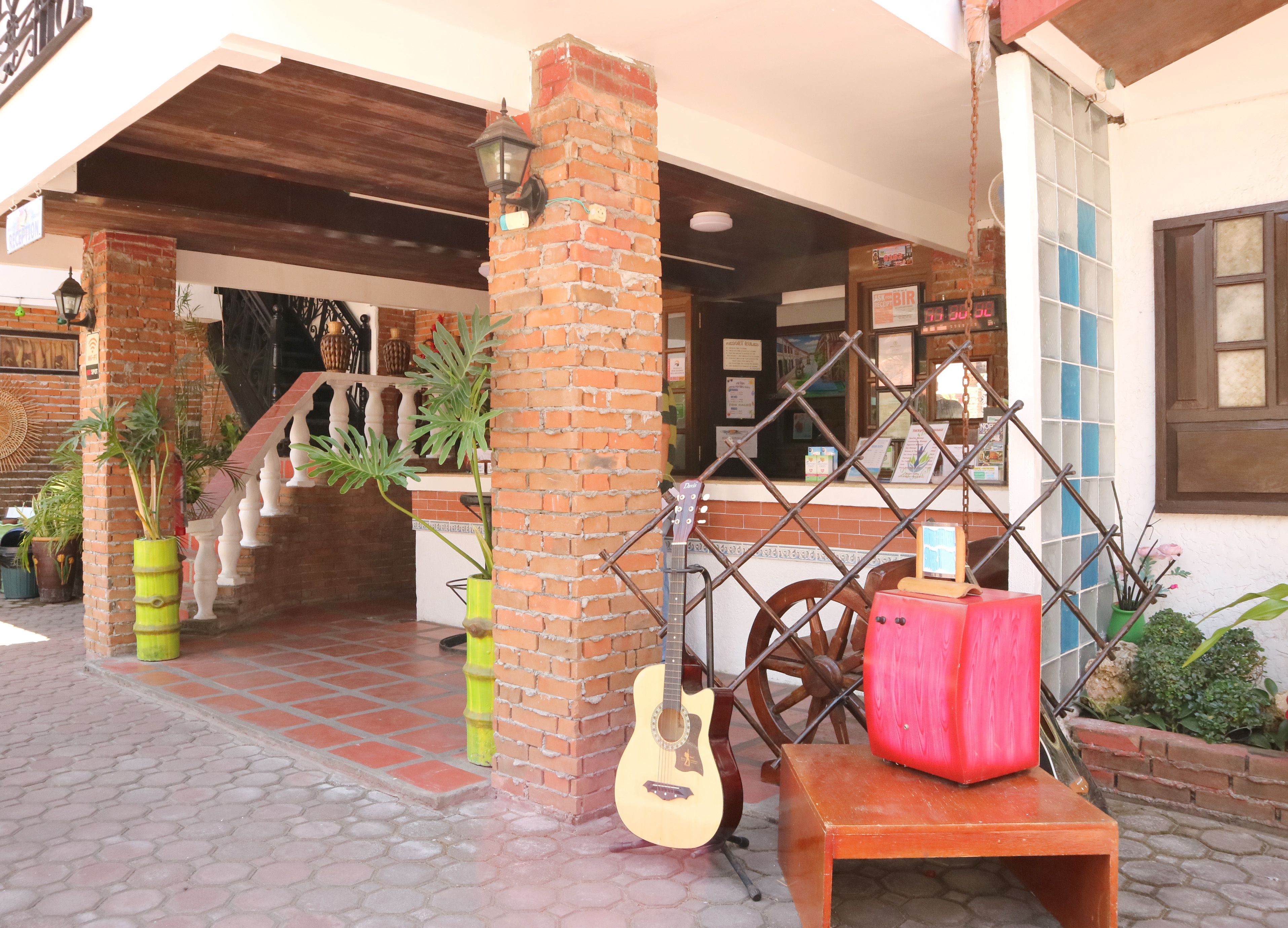 A brick building with a staircase, a guitar, and a red box on a bench.