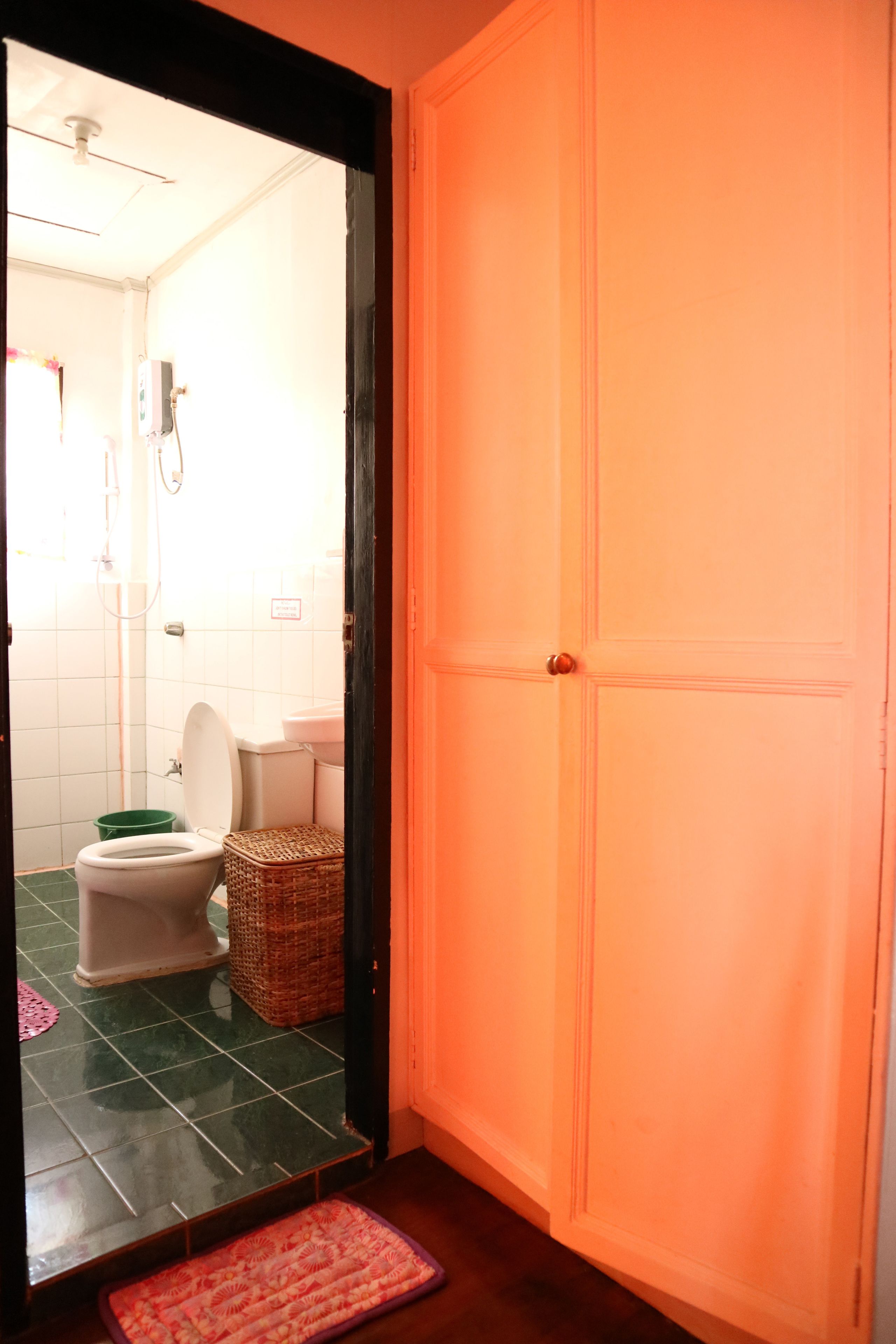 A bathroom with a toilet, a green trash bin, and a wicker basket.