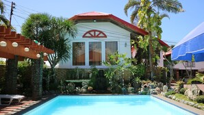 A swimming pool with a tiled edge, surrounded by rocks and plants. - Isla Bonita Beach Resort (San Juan)