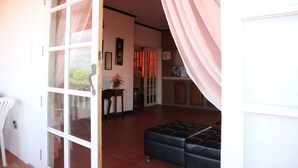 An open door leading to a living room with a black leather sofa, a white chair, and a fireplace. - Isla Bonita Beach Resort (San Juan)