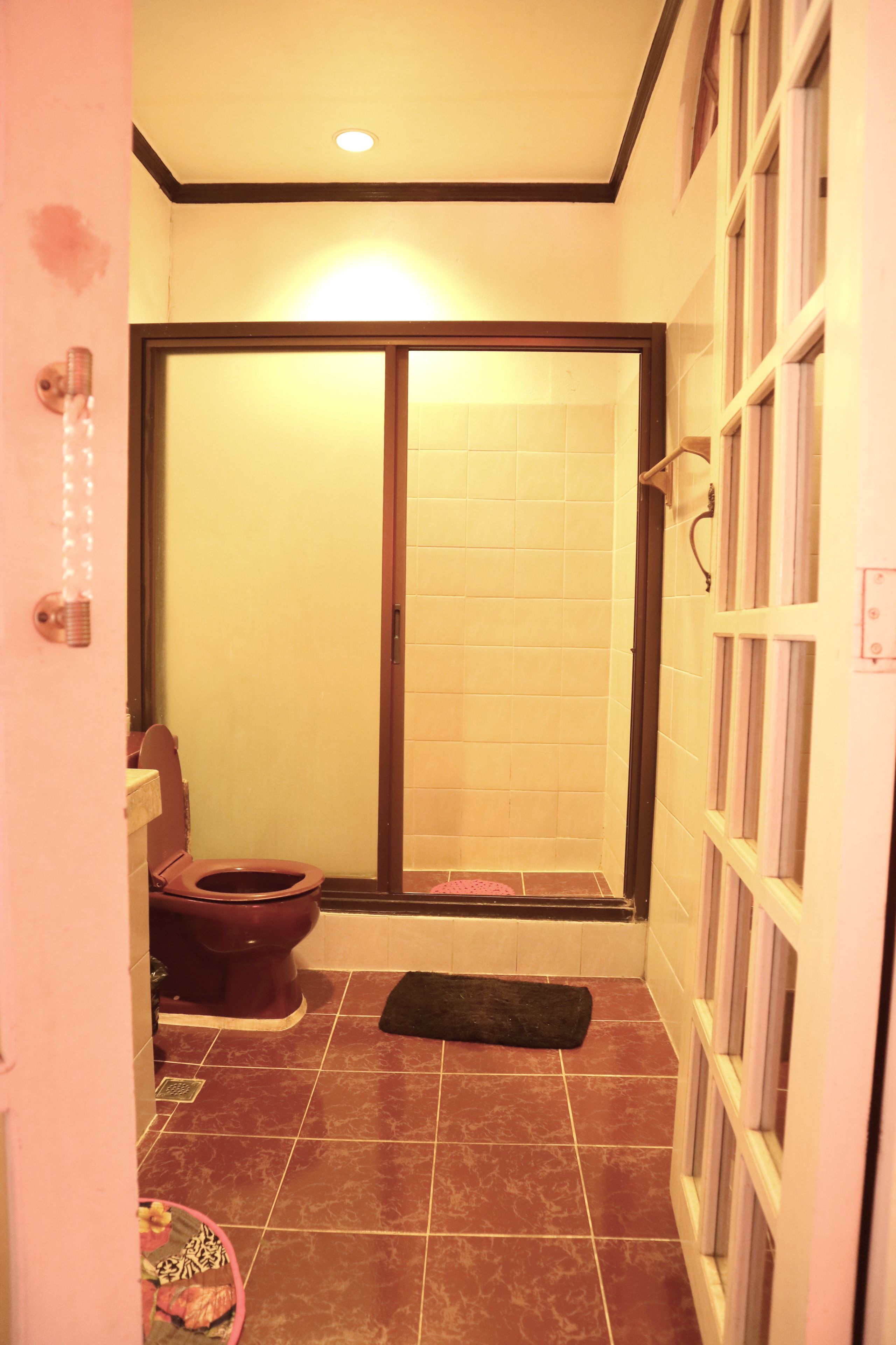 A bathroom with a toilet, a shower, and a tiled floor.
