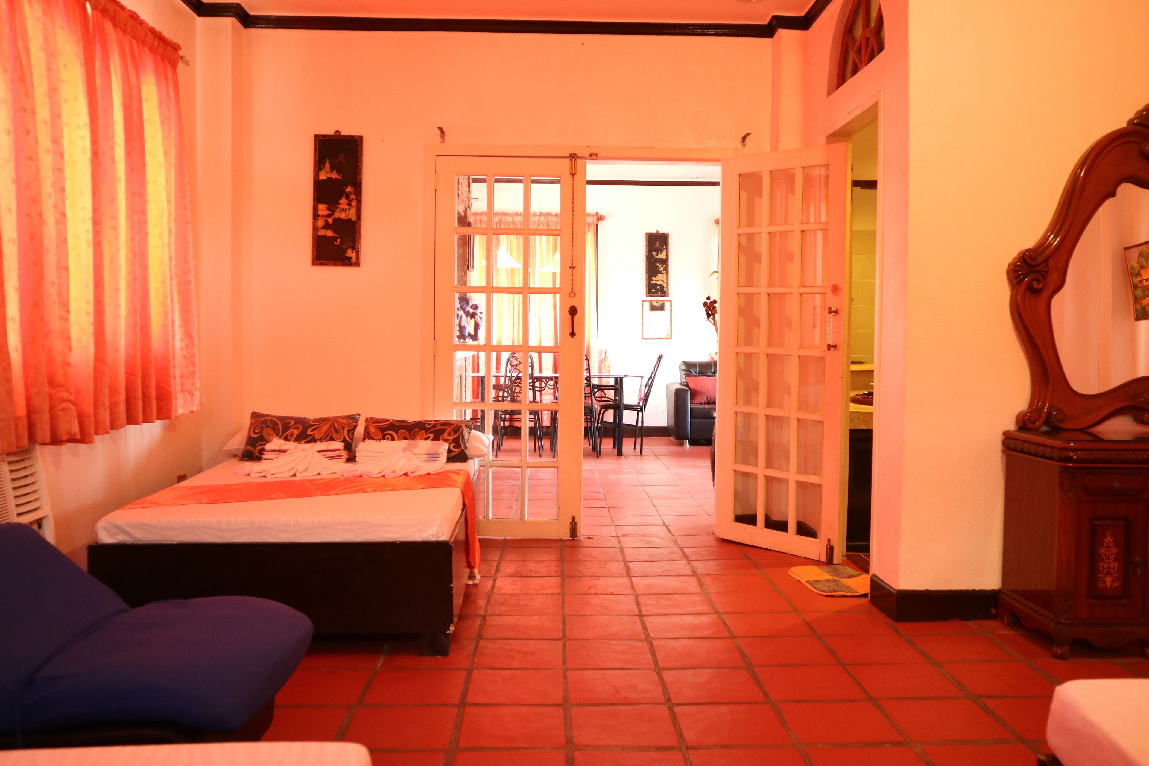 A hotel room with a bed, two chairs, a desk, and a wardrobe.