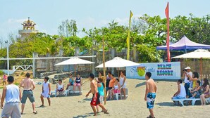 A beach volleyball game with players and spectators, a volleyball net, and a banner advertising a beach resort. - Isla Bonita Beach Resort (San Juan)