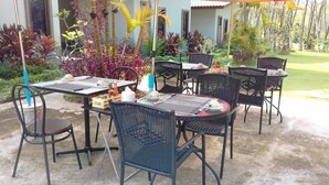 An outdoor patio with tables and chairs, surrounded by lush tropical plants. - Phuket Sirinapha Resort (Sa Khu)