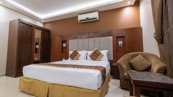 Una habitación de hotel con cama, una silla, una mesita de noche y un equipo de aire acondicionado.