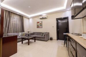 A modern living room with a sofa, coffee table, and a dining area with a kitchen counter. - Al Muhaidb Residence Al Malaz 1 - Economic (Riyadh)