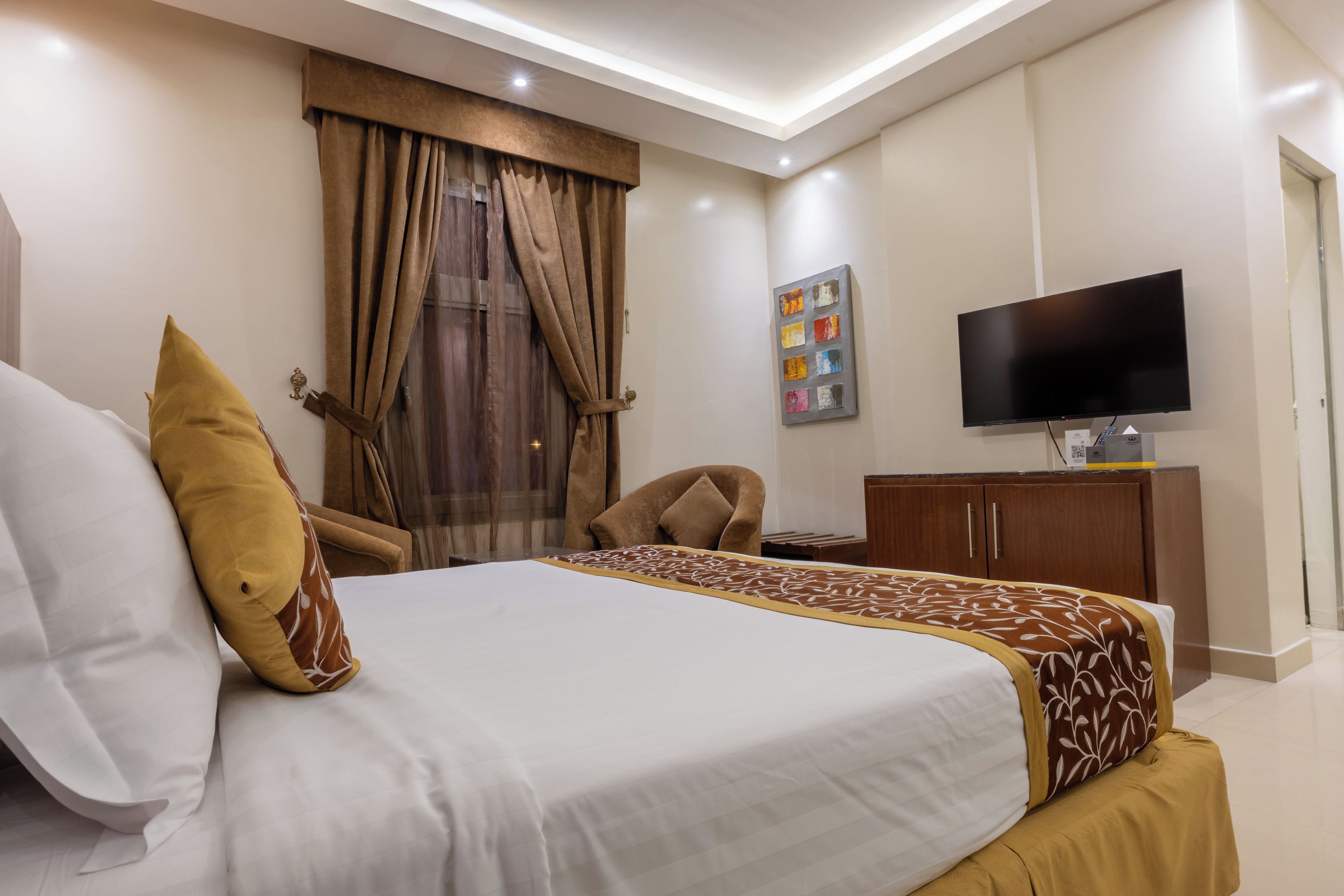 A hotel room with a bed, a television, a desk, and a chair.