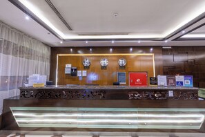 A hotel reception desk with clocks displaying London, Hong Kong, and Riyadh times.