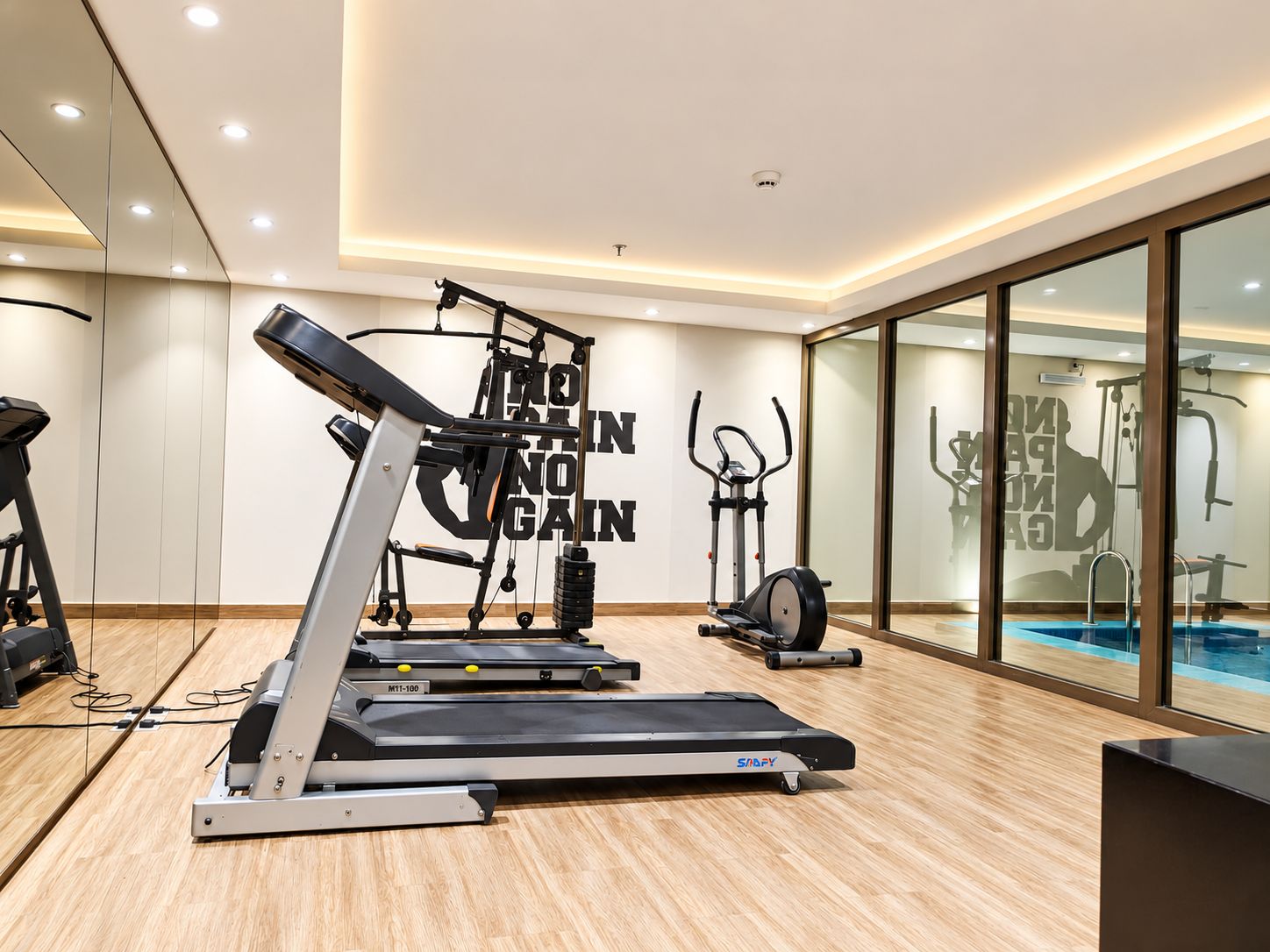 A modern gym with treadmills, a stationary bike, and a wall with motivational text.