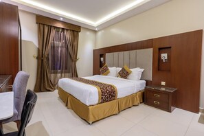 A hotel room with a bed, bedside table, chair, and curtains.