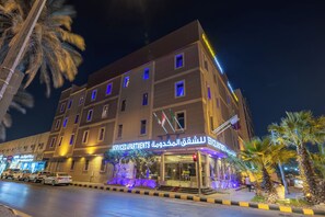 Um hotel com vários andares, fachada iluminada e entrada bem iluminada.