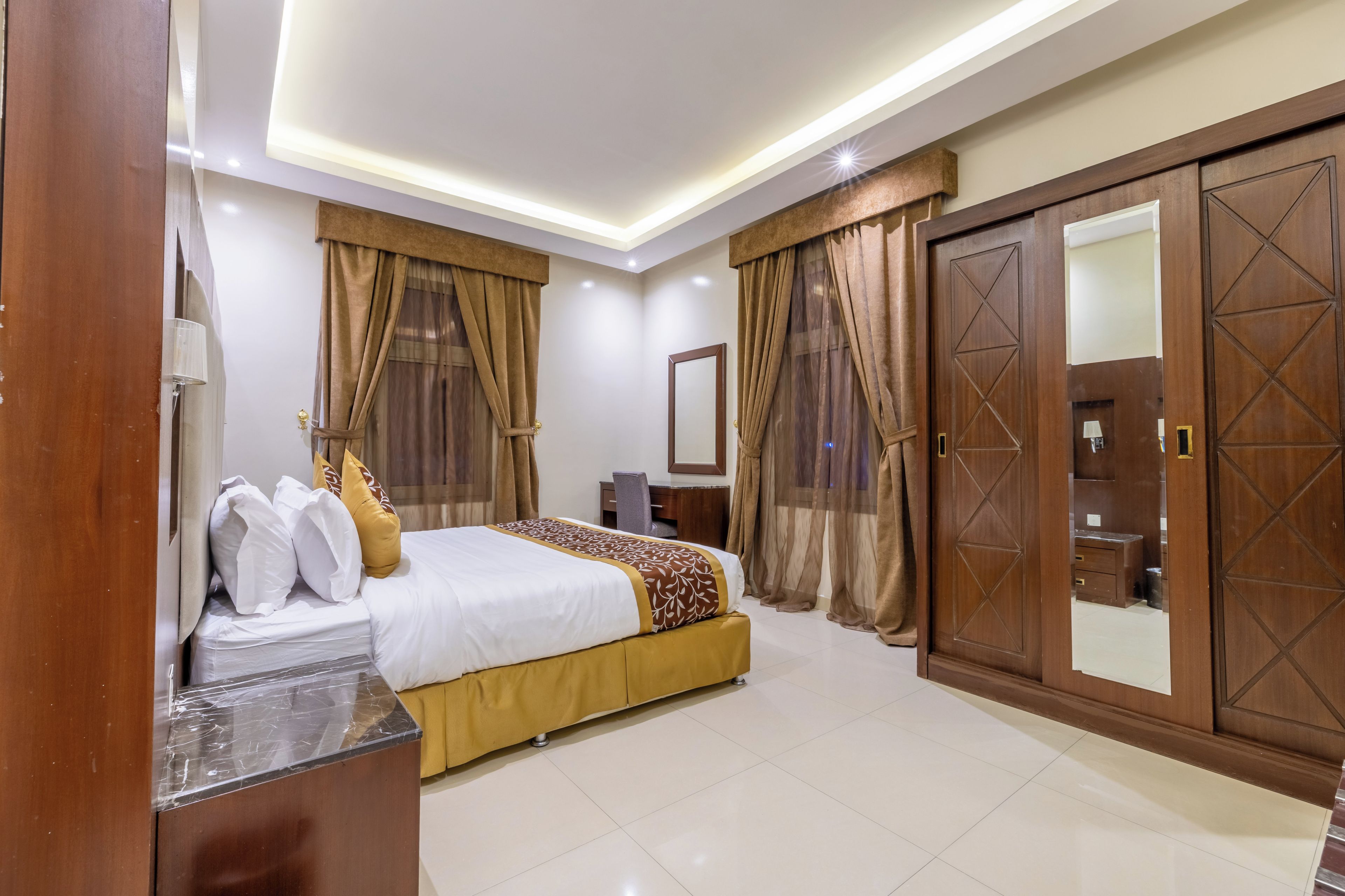 A hotel room with a bed, a desk, a wardrobe, and a bathroom.