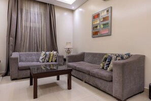 A living room with two grey sofas, a glass coffee table, and a lamp. - Al Muhaidb Residence Al Malaz 1 - Economic (Riyadh)