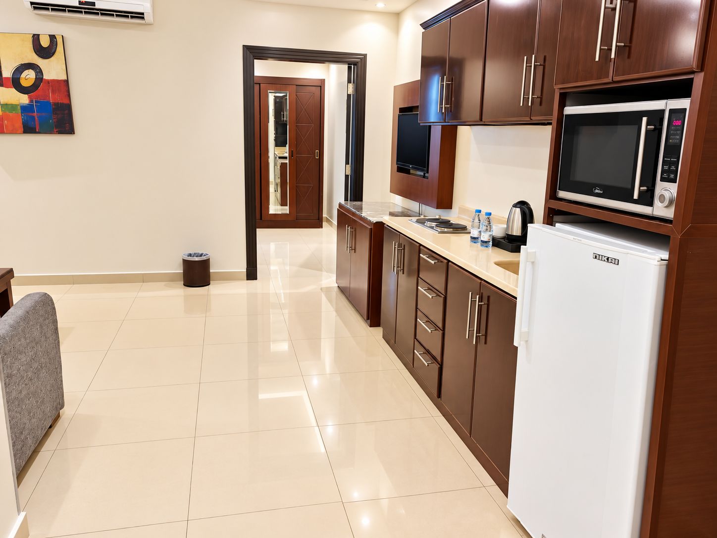 A modern kitchen with a microwave, refrigerator, and wooden cabinets.