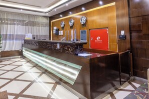 A reception desk with clocks, a fire hose cabinet, and a patterned floor. - Al Muhaidb Residence Al Malaz 1 - Economic (Riyadh)