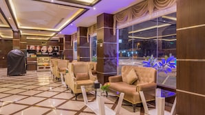 A hotel lobby with a check-in counter, seating area with armchairs, a glass coffee table, and large windows with curtains. - Al Muhaidb Residence Al Malaz 1 - Economic (Riyadh)