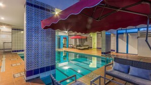 An indoor swimming pool with tiled walls, a red canopy, and a seating area with a sofa and chairs. - Al Muhaidb Residence Al olaya 2 - Economic (Riyadh)
