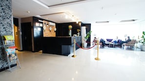 A hotel reception area with a black reception desk, a clock, and a red rope barrier. - Al Muhaidb Residence Al olaya 2 - Economic (Riyadh)