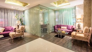 A modern living room with two purple sofas, a glass partition, and a wooden floor. - Al Muhaidb Residence Al olaya 2 - Economic (Riyadh)