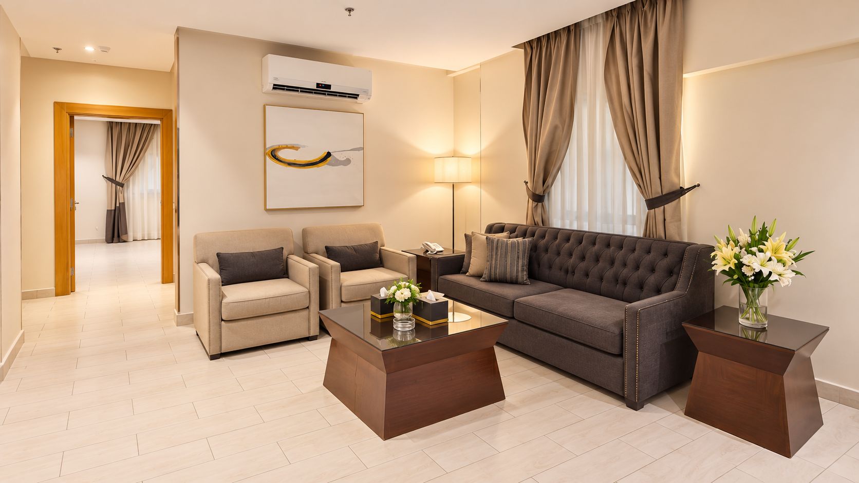 A modern living room with a sofa, two armchairs, a coffee table, and a lamp.