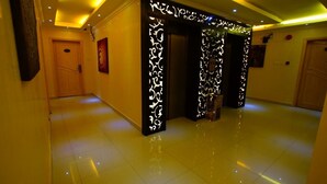 A hallway with a wooden door, a decorative wall panel, and a tiled floor. - Al Muhaidb Residence Al olaya 2 - Economic (Riyadh)