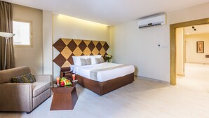 A hotel room with a large bed, a sofa, a small table with fruit and a drink, and a window with curtains. - Al Muhaidb Residence Al olaya 2 - Economic (Riyadh)