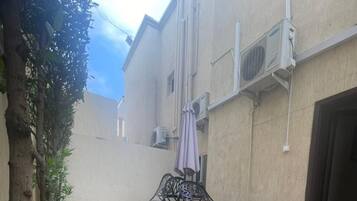 A building with air conditioning units, a tiled patio, and a metal table with chairs.