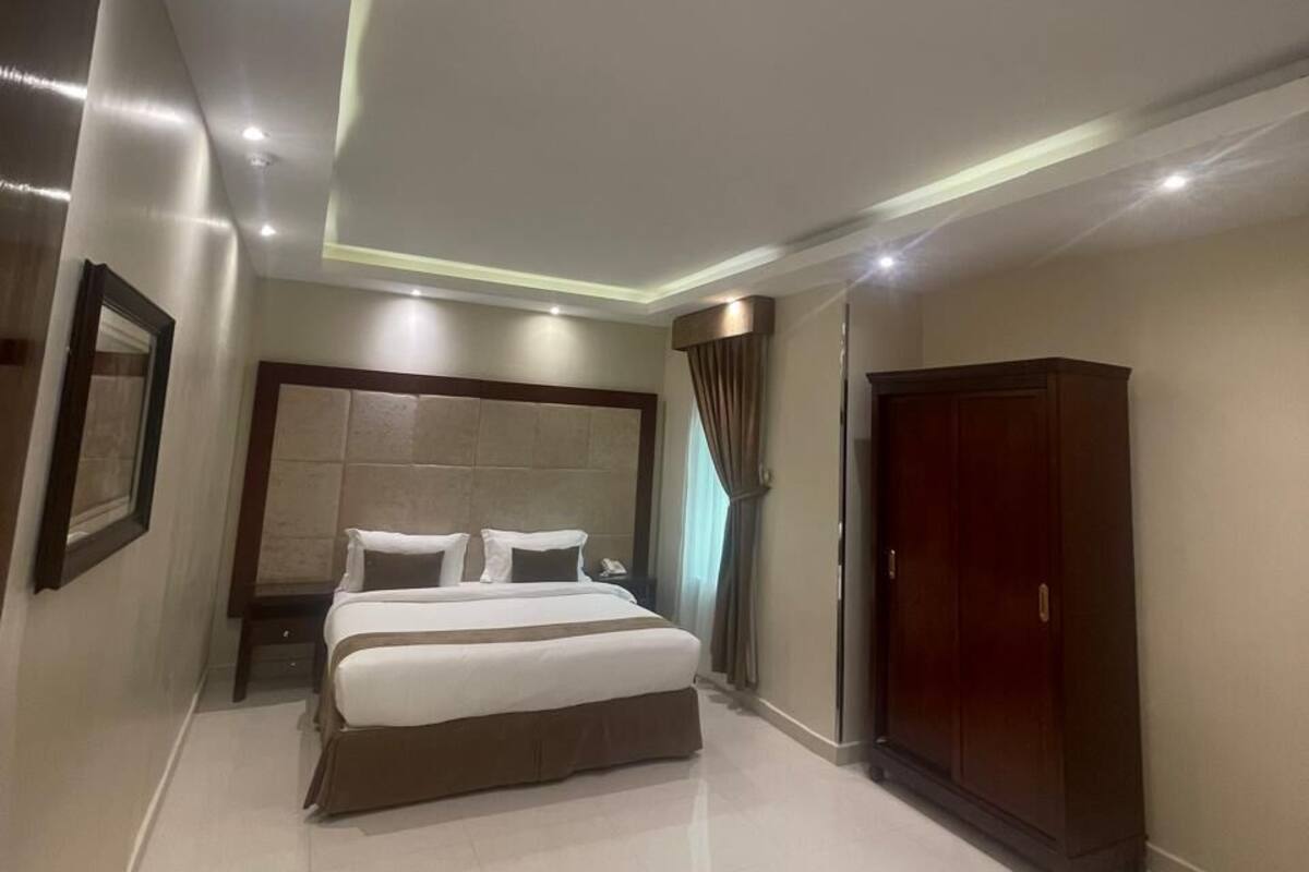 A modern hotel room with a large bed, a wardrobe, and a mirror.