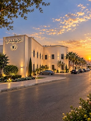 A hotel with a modern facade, a parking area, and a sunset sky.