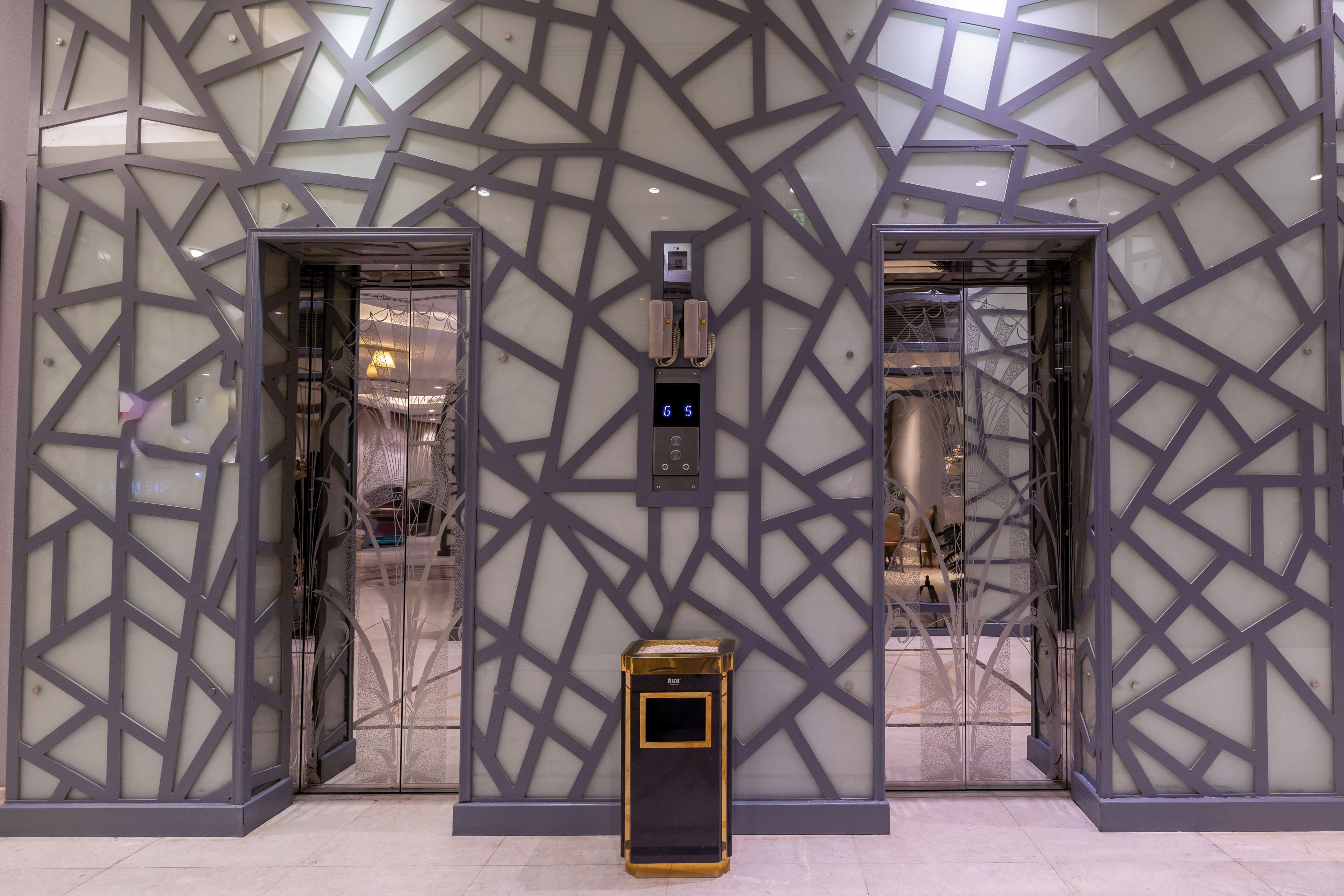 A modern elevator with a geometric glass facade and a digital control panel.