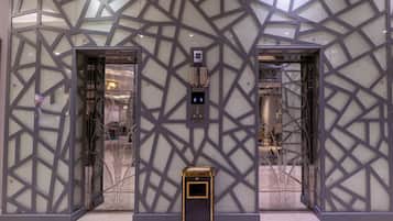 A modern elevator with a geometric glass facade and a digital control panel.