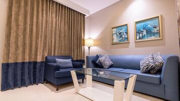 Uma sala de estar moderna com um sofá azul, uma mesa de centro de vidro e uma luminária.