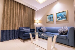 A modern living room with a blue sofa, a glass coffee table, and a lamp. - Al Muhaidb Residence Al Malaz 2 - Economic (Riyadh)