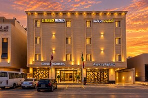 A hotel with a sign indicating 'Service Apartments' and flags in front. - Al Muhaidb  Residence Al Narges - Economic (Riyadh)