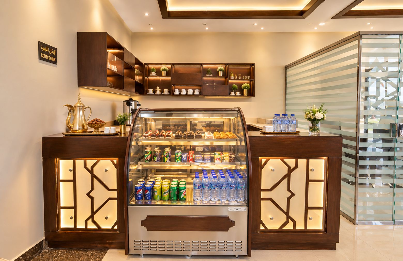 A coffee corner with a display case containing pastries and a selection of beverages.