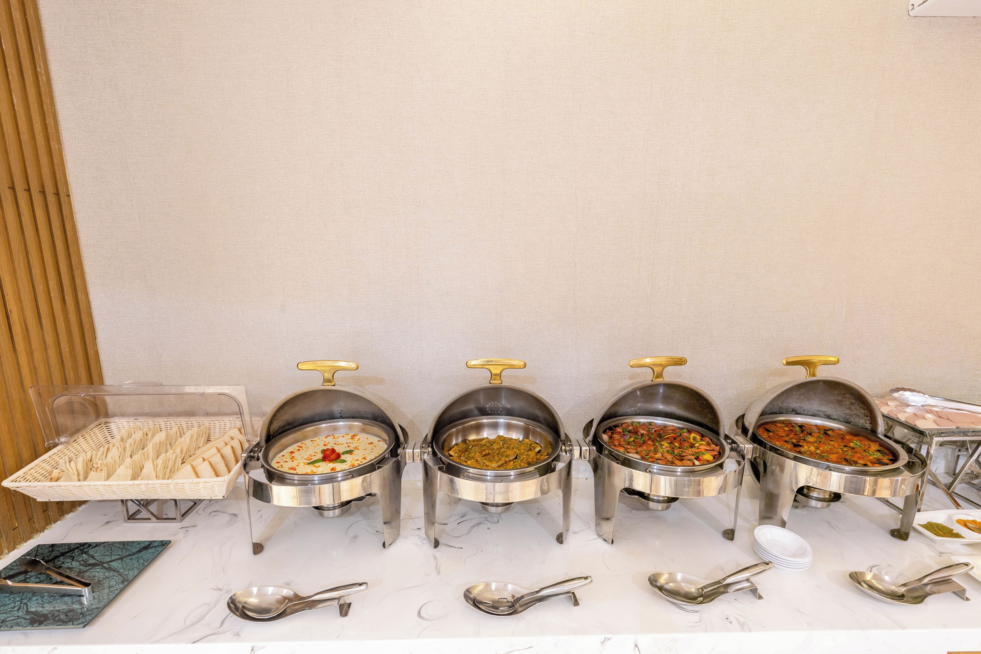 A buffet setup with various food containers and serving utensils.