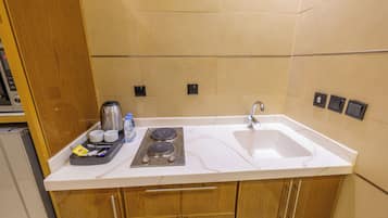 A kitchen with a white countertop, two sinks, a stove, and wooden cabinets.