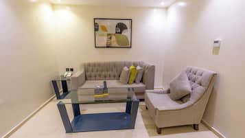 A modern living room with a glass coffee table, a tufted sofa, and a cushioned armchair.