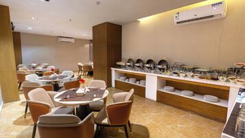Un comedor moderno con mesas redondas, sillas y un mostrador tipo buffet.