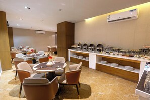 Un comedor moderno con mesas redondas, sillas y un mostrador tipo buffet.