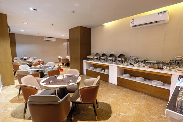 A modern dining area with round tables, chairs, and a buffet counter. - Al MuhaidbResidence Al Takhasossi 1 - Economic (Riyadh)