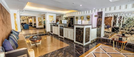 A hotel lobby with a reception desk, seating area, and a check-in counter.